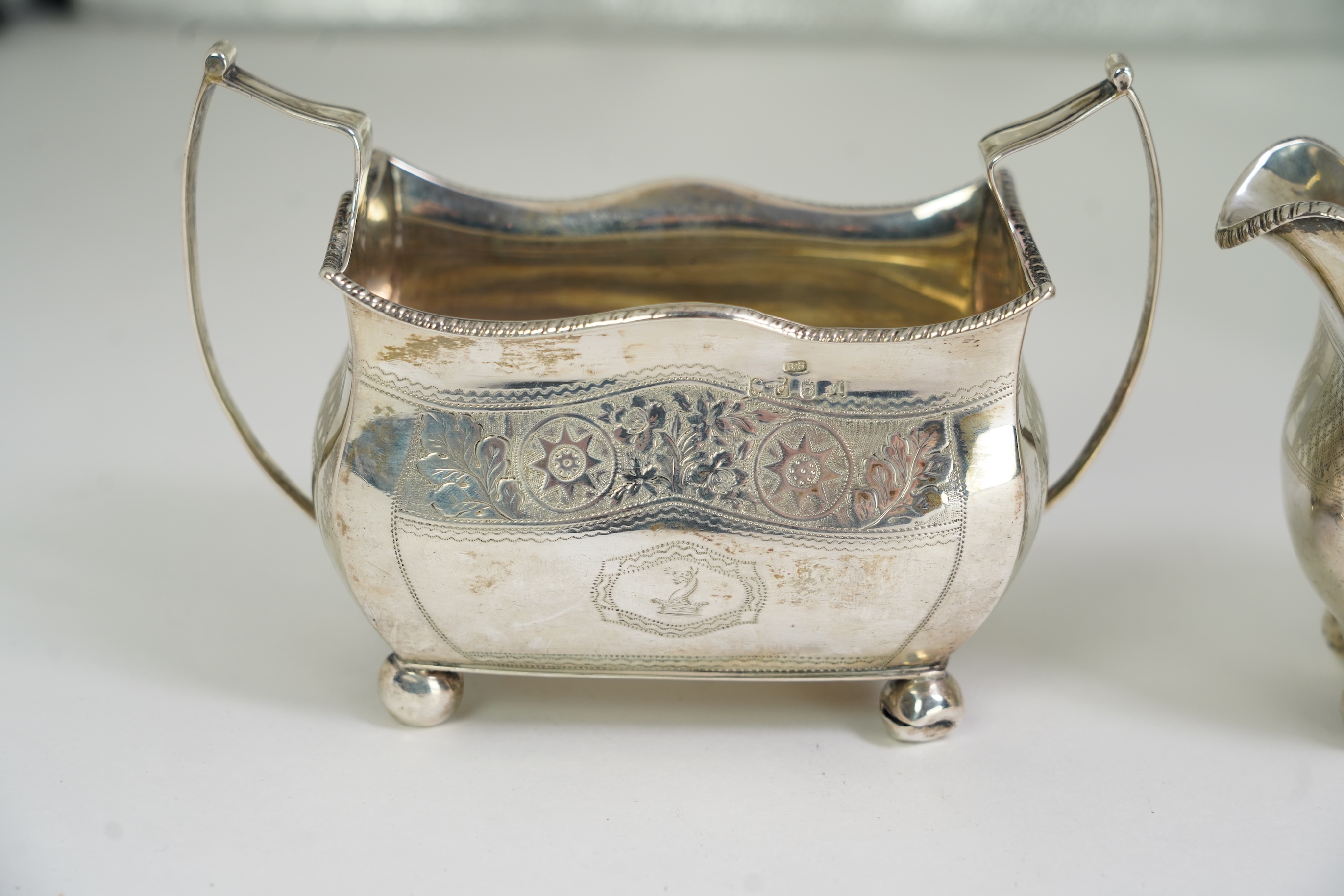 A George III Irish silver two handled sugar bowl, by Richard Sawyer, Dublin, 1808, 18.4cm over handles, with engraved armorial, on four ball feet, together with a similar cream jug, by Daniel Egan, Dublin, 1811, 16.2oz.